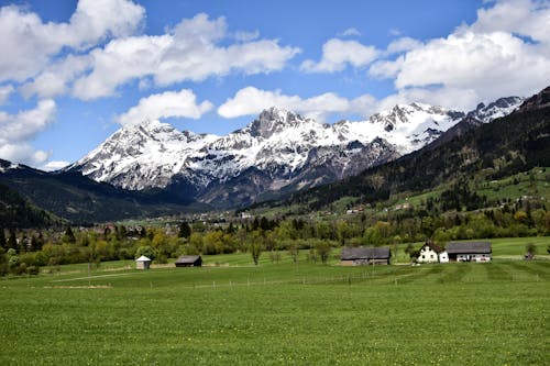 Landscape Photography of Green Grass Field Near Snow Capped Mountains