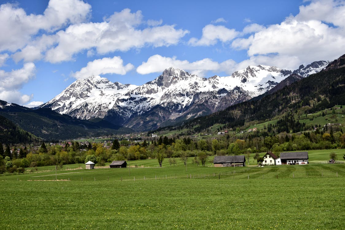 Landscape Photography of Green Grass Field Near Snow Capped Mountains