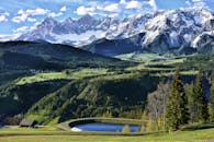 在明亮的蓝天下，壮丽的高山山脉与绿色山谷构成完美的旅行目的地