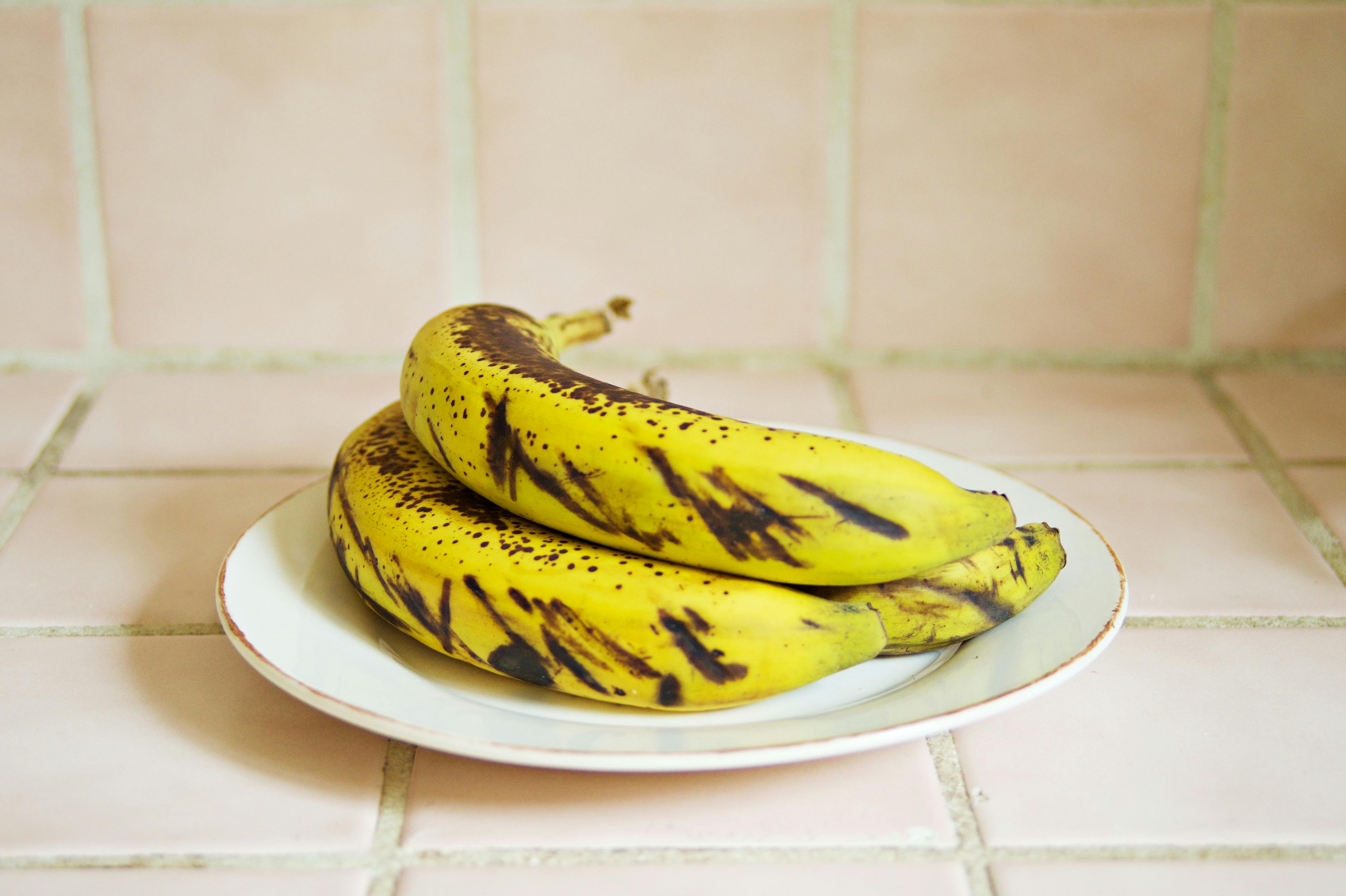 Close-up of fresh ripe bananas on a white ceramic plate indoors.