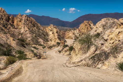 Free A winding dirt road through a scenic rocky desert canyon under a clear blue sky. Stock Photo