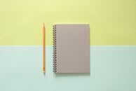 在柔和的背景上，螺旋笔记本和铅笔平放着，非常适合学校和办公室主题