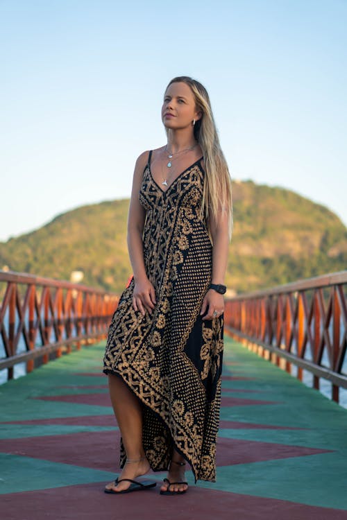Free Woman in a Black and Gold Dress Standing on a Bridge Stock Photo
