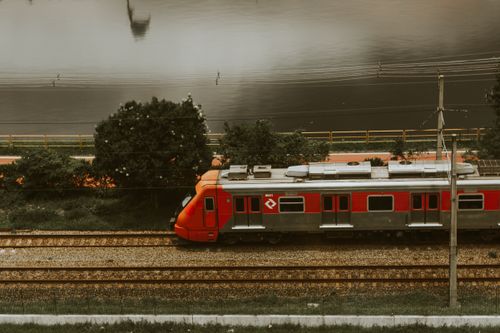 Free Aerial view of a red train passing through urban tracks beside a river in São Paulo. Stock Photo