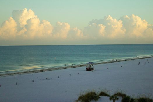 A serene view of Clearwater Beach, featuring a lifeguard post, expansive sand, and a tranquil ocean beneath a clear blue sky.