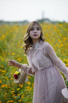 一位穿着花香连衣裙的时尚女人，提着篮子，走在阳光明媚的草地上