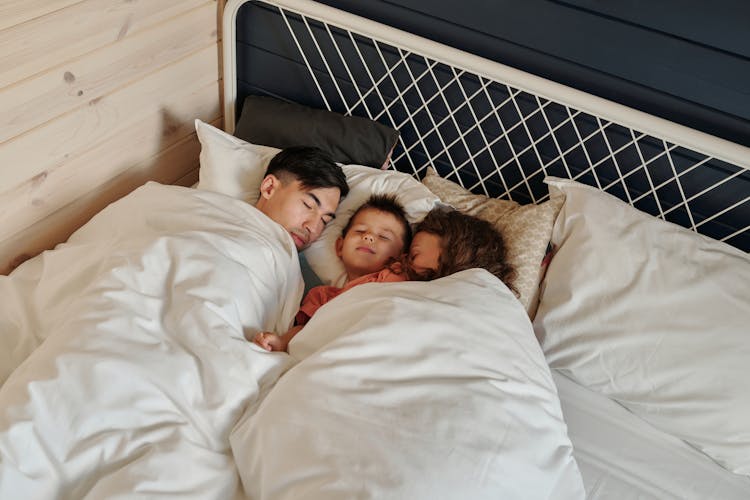 A Family Sleeping On The Bed