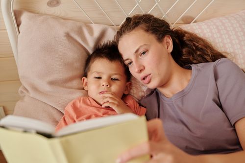 Free A mother and son bonding while reading a bedtime story together in their cozy bedroom. Stock Photo