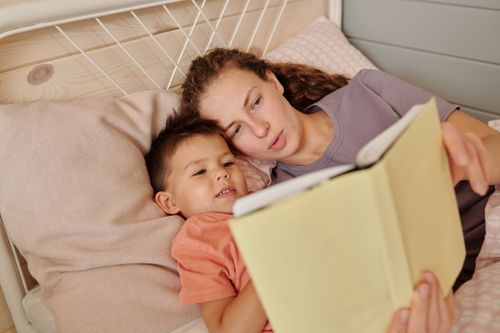 Free Mother and son reading a book together, enjoying a cozy and bonding moment in bed. Stock Photo