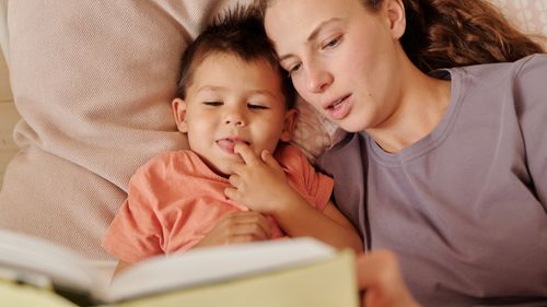 Free A loving mother and her young son enjoy reading a book together in bed. Captured in a cozy home setting. Stock Photo