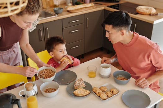 A joyful family of three sharing breakfast in a cozy kitchen setting, featuring waffles and cereal.