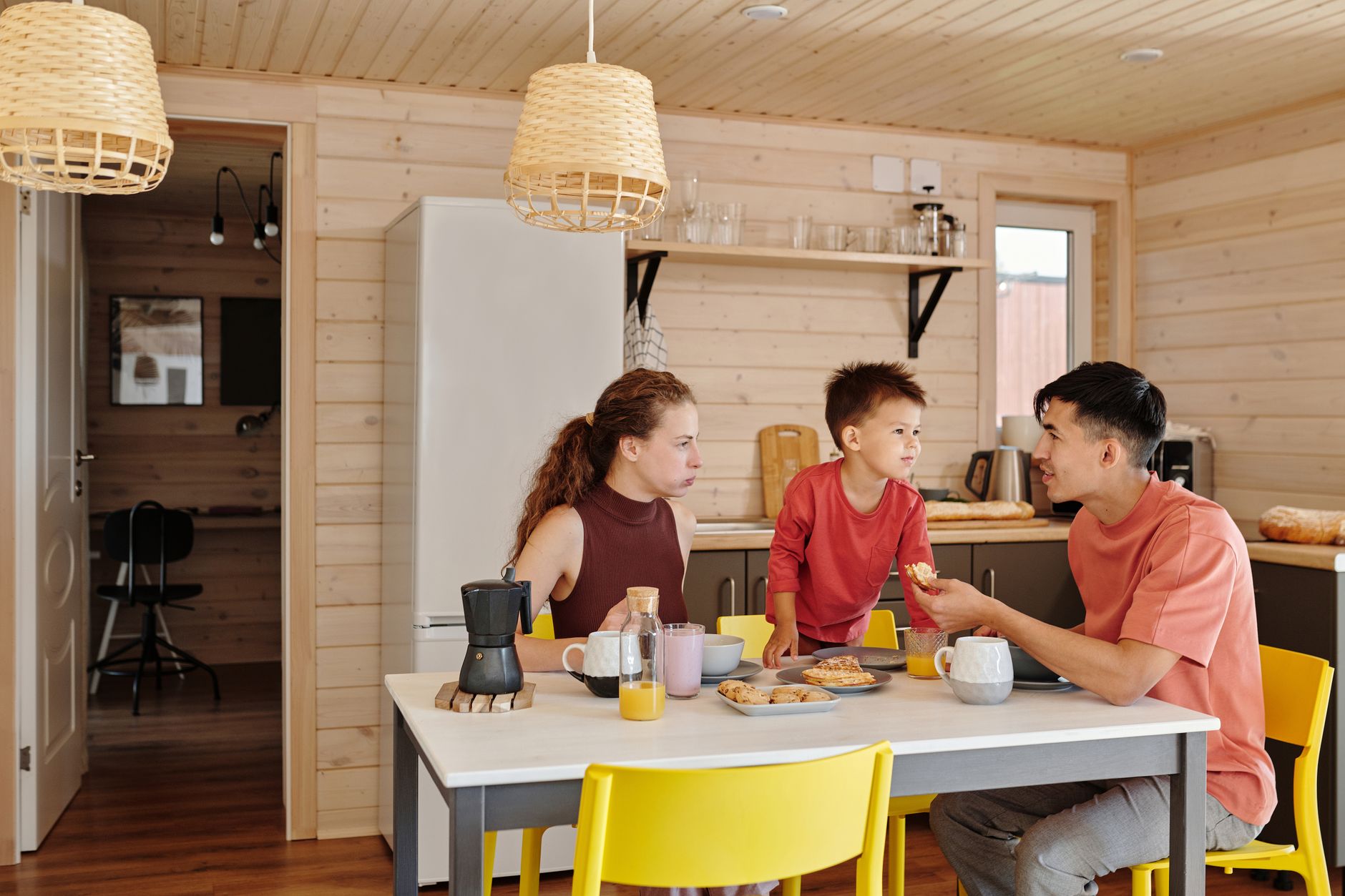 Happy family enjoying breakfast together in a cozy, modern kitchen setting with warm wooden interiors.