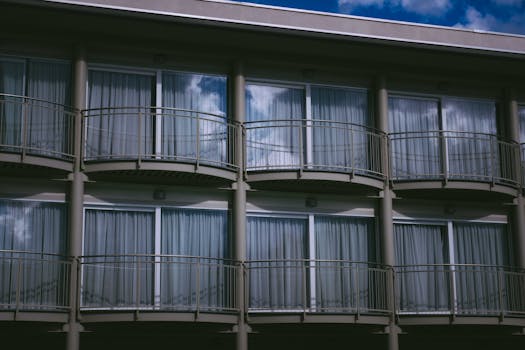 From below balconies with railings and large glass doors and windows with curtains