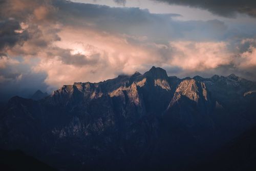 Free Magnificent scenery of high rocky mountains and clouds illuminated by sunlight in evening Stock Photo