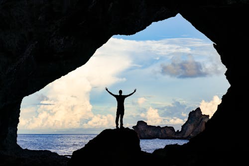Silhouette of a Man Standing Inside a Cave
