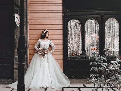 A bride in a stylish gown poses elegantly against a classic urban backdrop in Tehran.