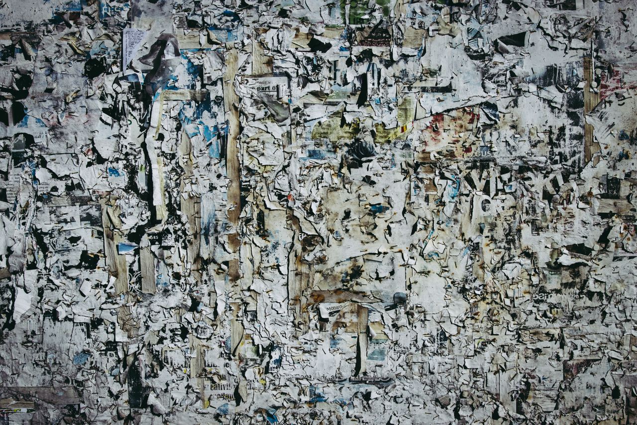 a textured wall with layers of torn and weathered paper for artistic b