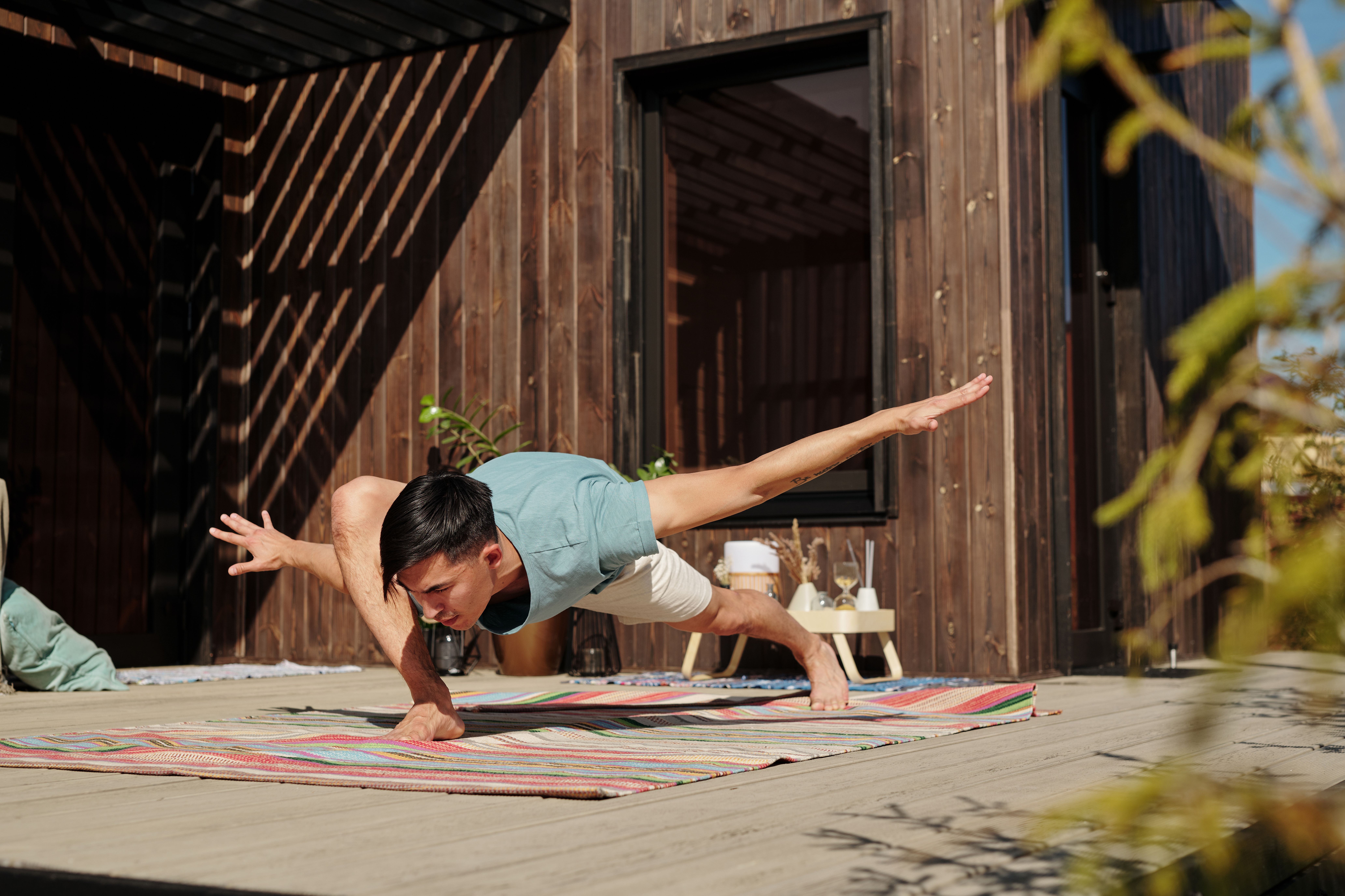 An experienced yogi holds a steady posture on a mat in warm veranda light.