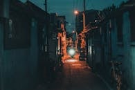 A Man Riding a Motorcycle Passing on the Narrow Street Between Houses