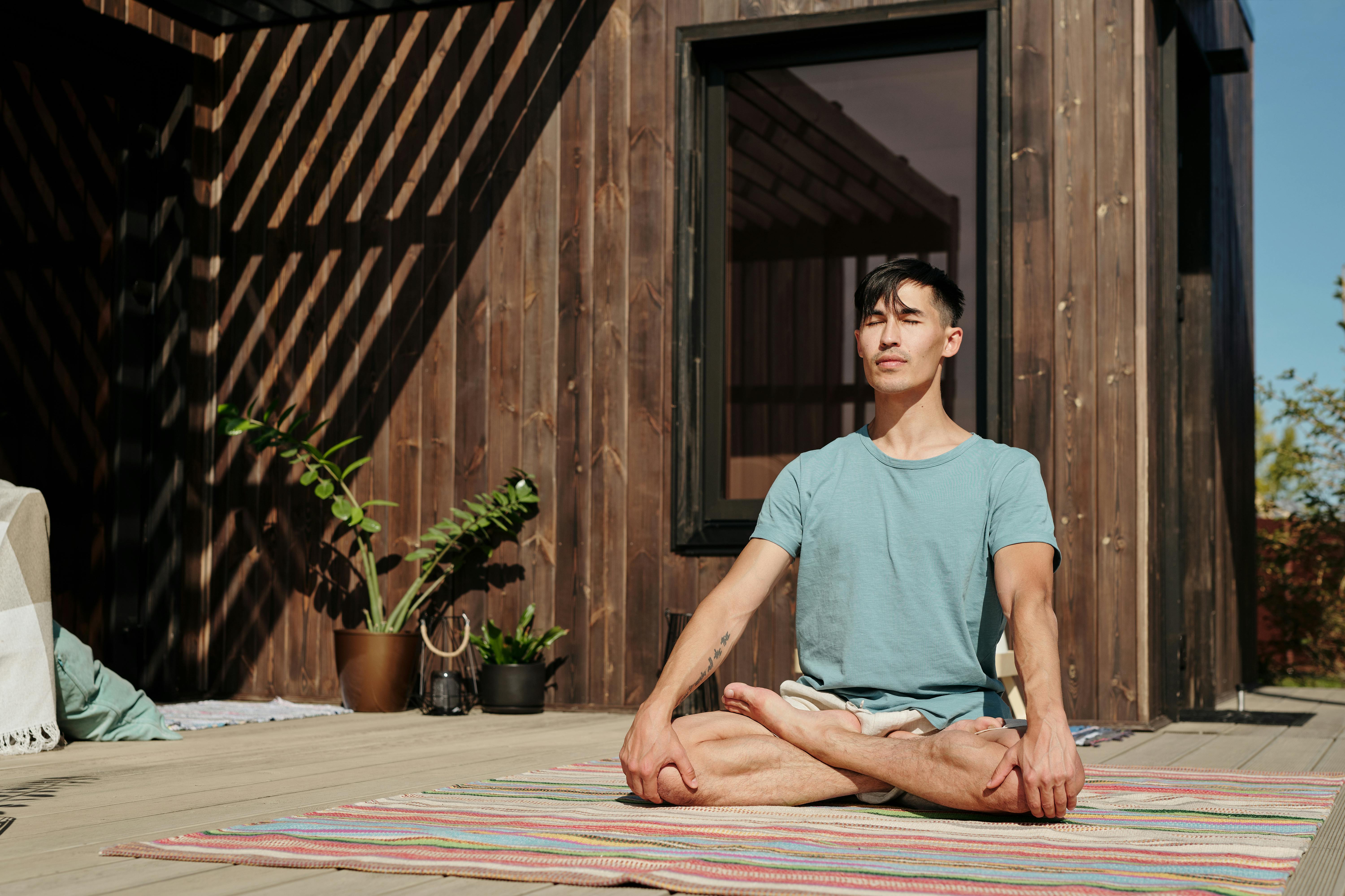 Man meditating outdoors with closed eyes, enjoying a peaceful moment on a sunny day.