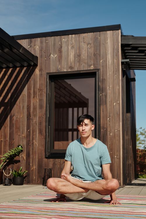 Free Adult man meditating outdoors in the lotus pose, enjoying a sunny day. Stock Photo