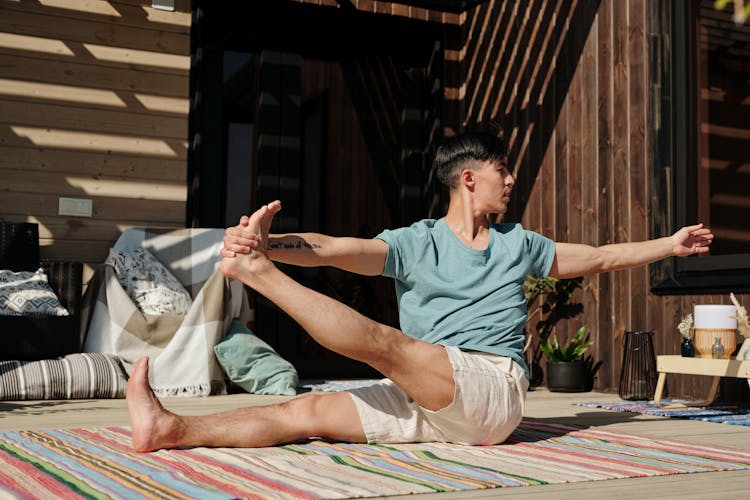 Man In Teal Crew Neck T-shirt In Leg Stretch Pose