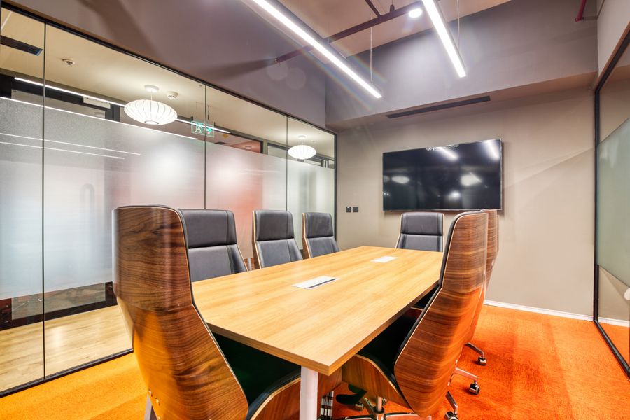 Glass walled boardroom with a long table and upholstered chairs
