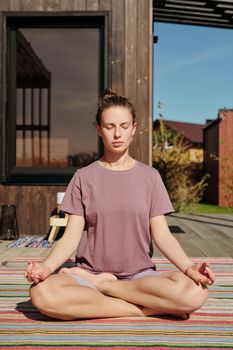 A woman in lotus pose meditating outdoors on a sunny day, enjoying inner peace.