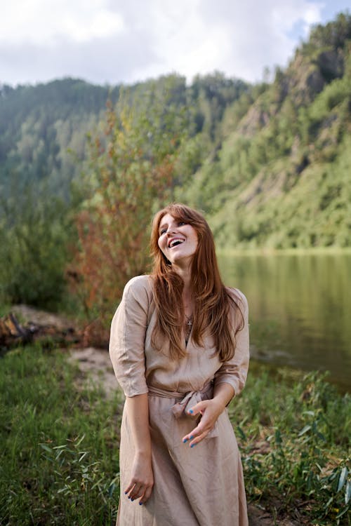 Happy woman against greenery mountain and pond
