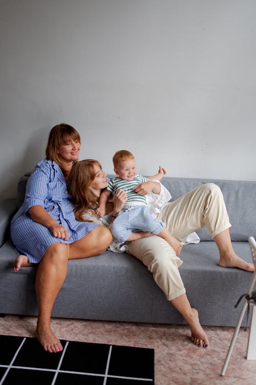 Positive granny and daughter with baby having fun on couch