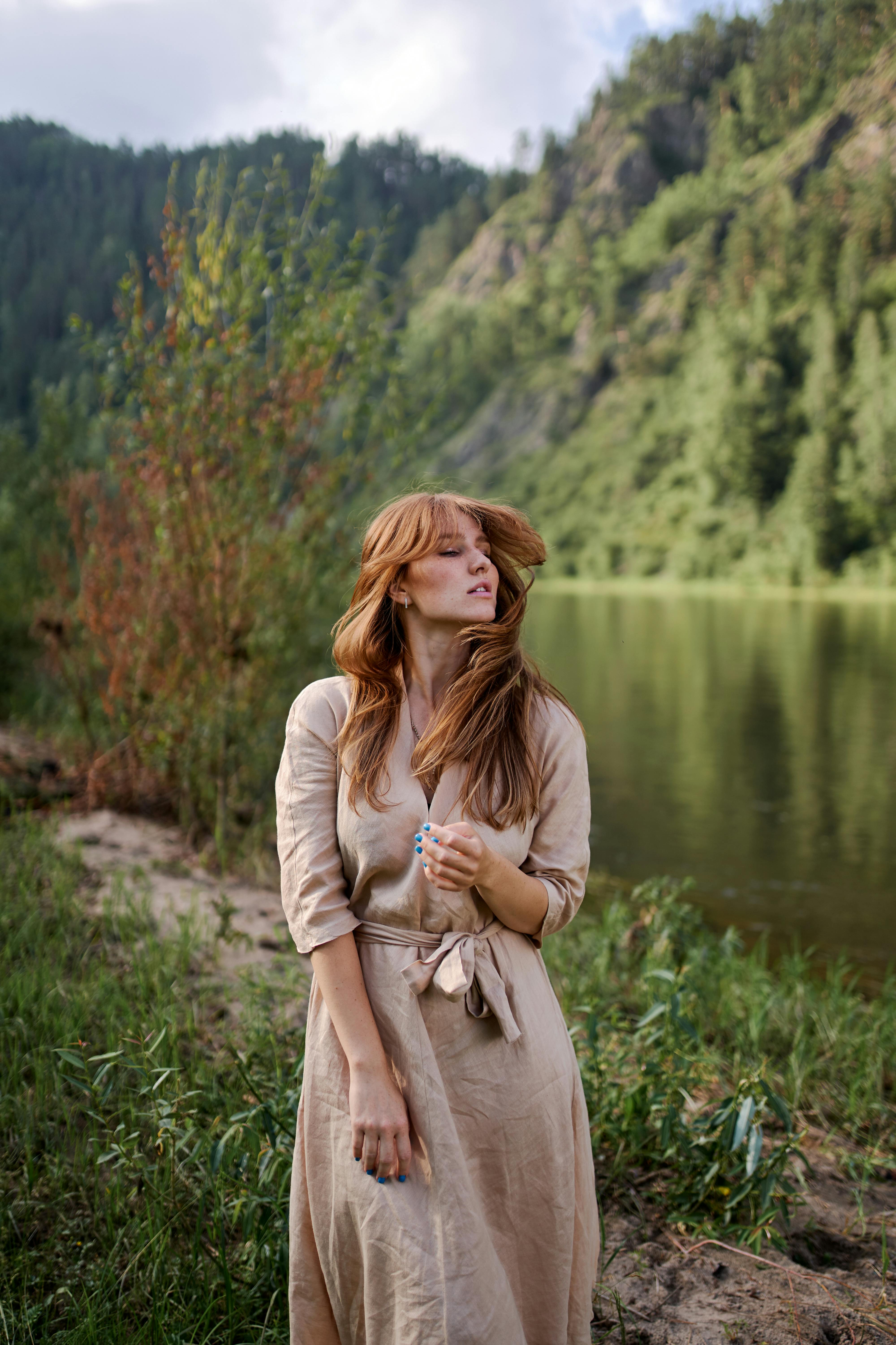 夏日里，一位身着米色连衣裙的女子在河边享受着宁静的时光