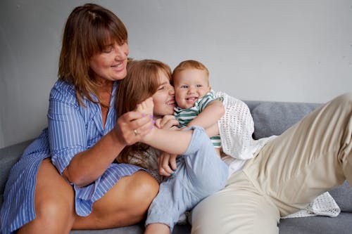 Free Happy grandmother with daughter and little boy resting on cozy couch in living room Stock Photo