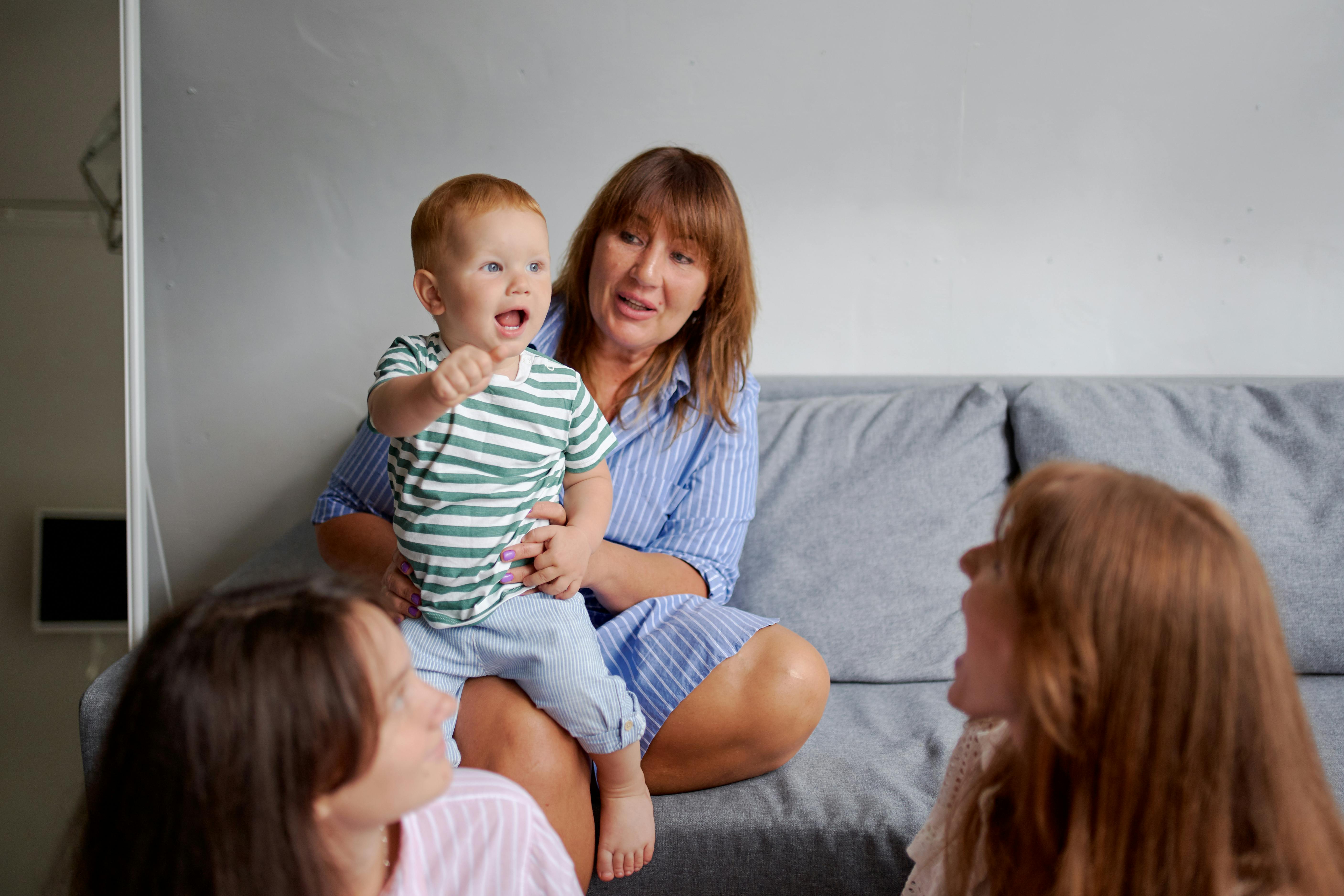 smiling grandma with little boy on sofa near daughters