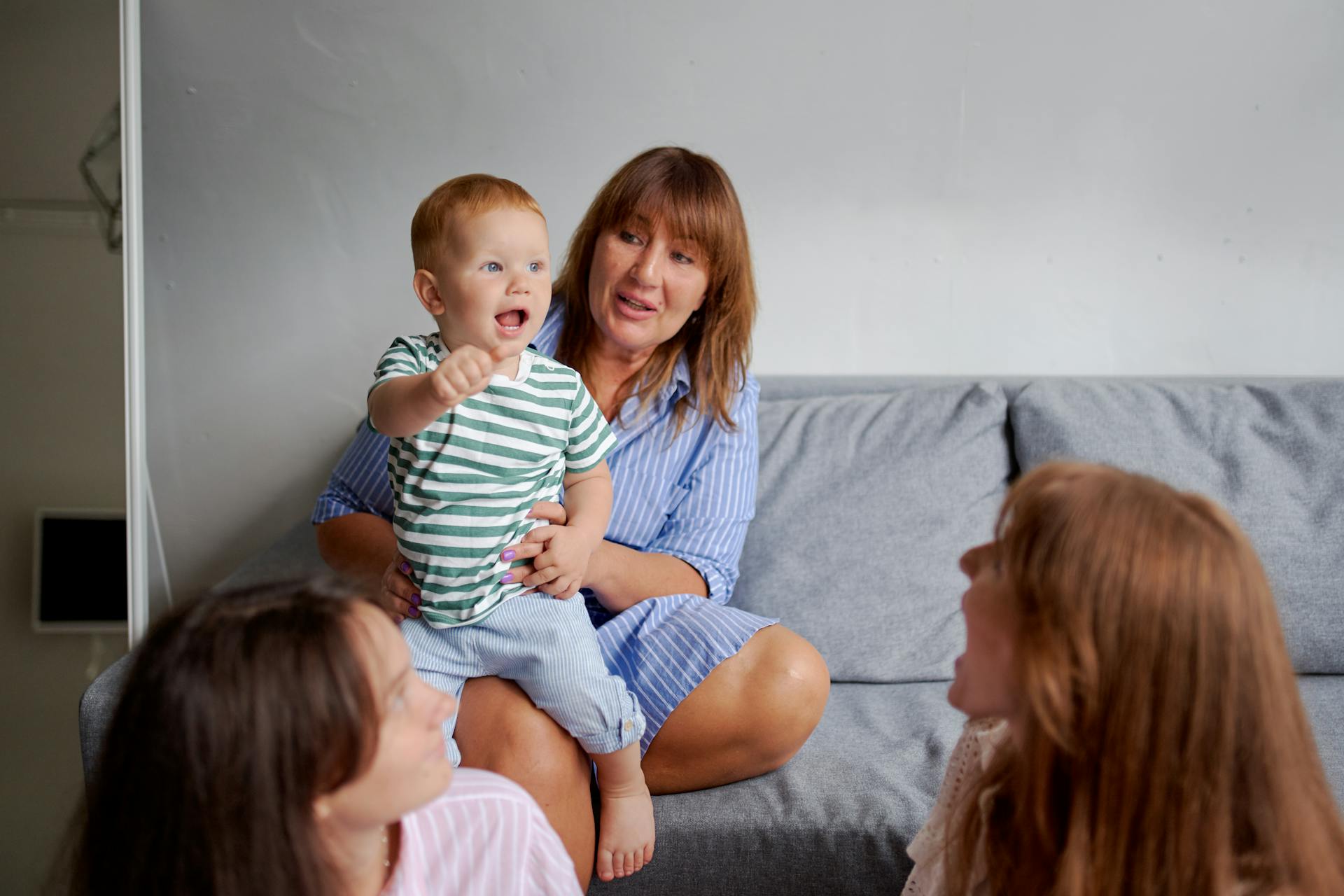 A cheerful family gathering indoors with three generations enjoying quality time on a sofa.