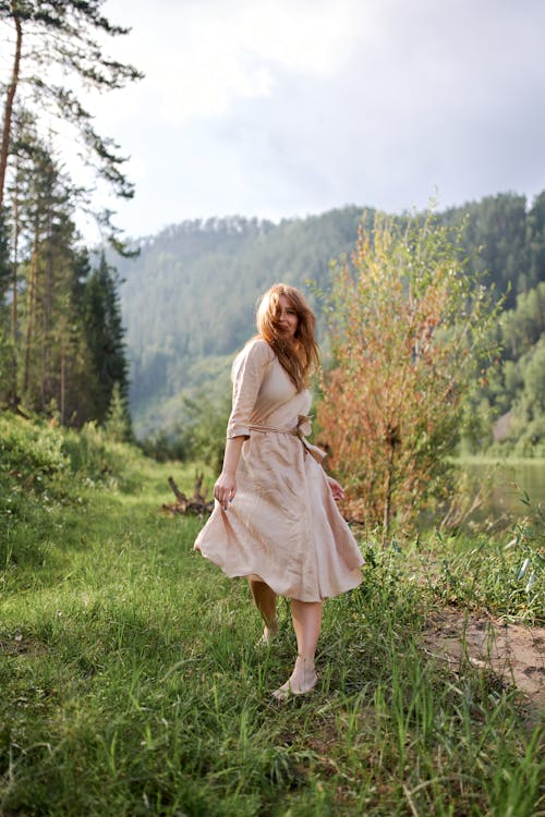 Carefree barefoot woman on green river coast in summer