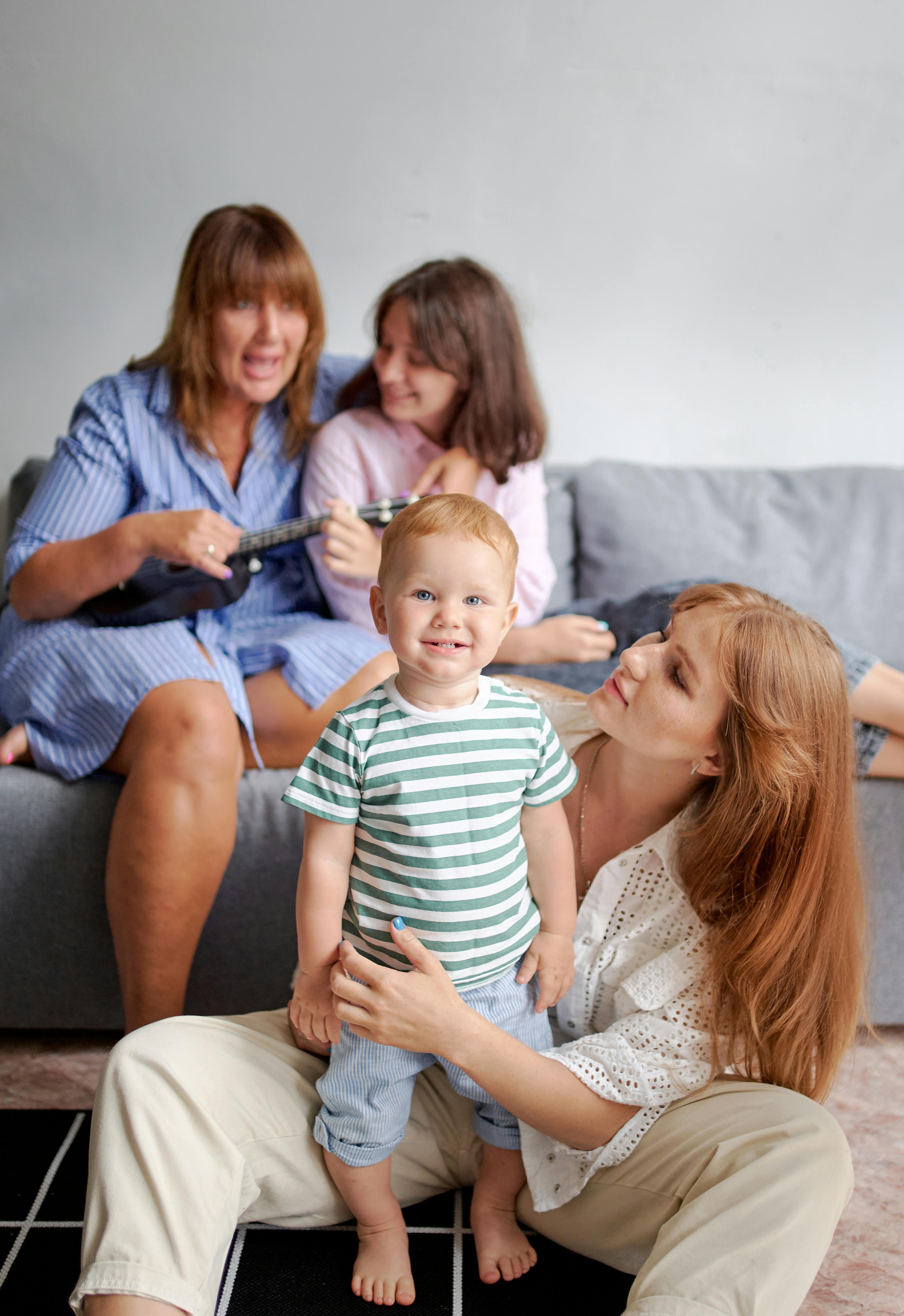 mother with smiling baby near relatives on sofa