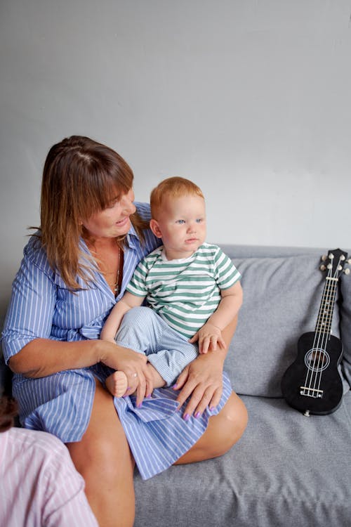 Free Smiling grandmother resting with cute baby on sofa Stock Photo