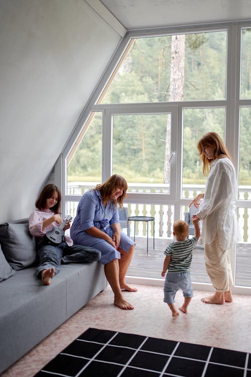 Mother with anonymous little son near grandma and sister on couch in countryside house