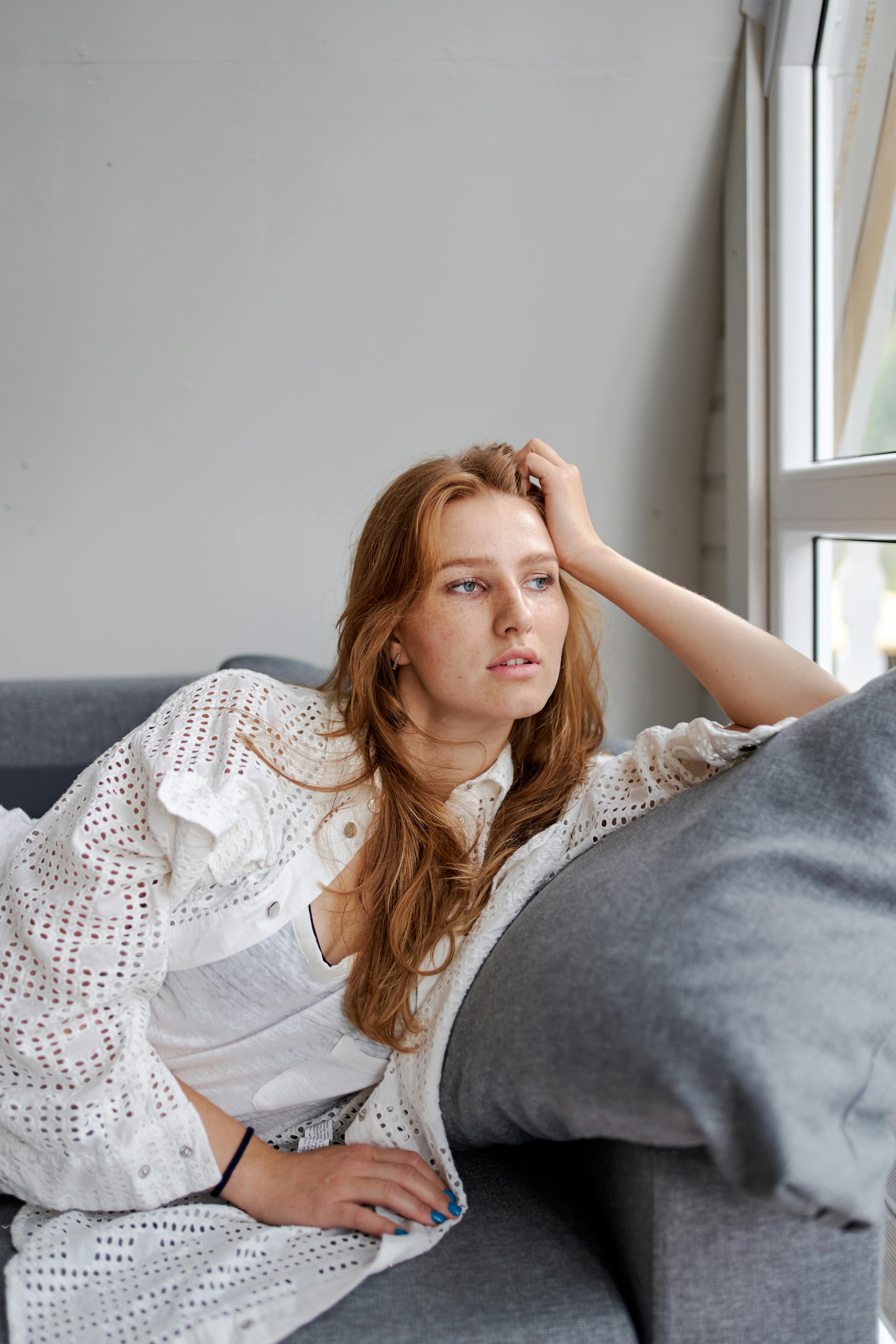 dreamy woman leaned with hand on sofa in room