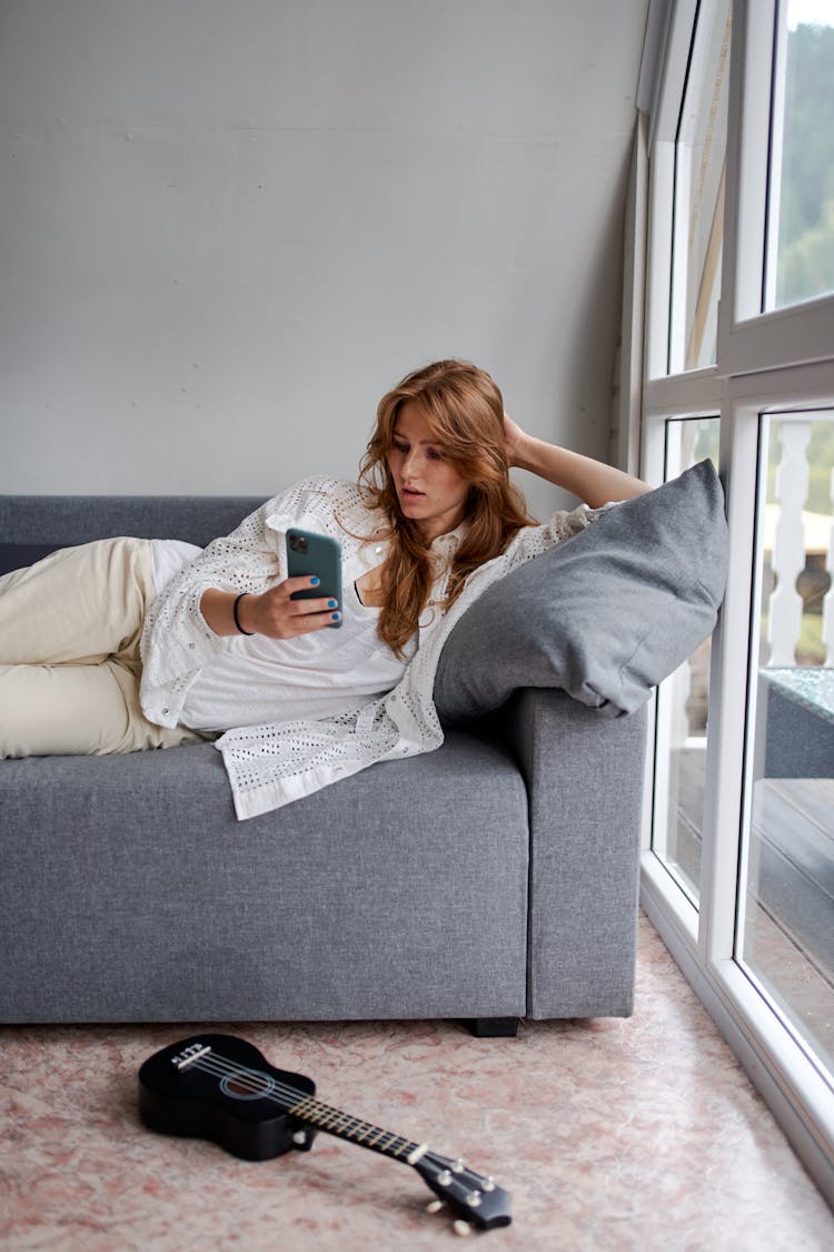 Attentive Woman Surfing Internet On Smartphone On Sofa