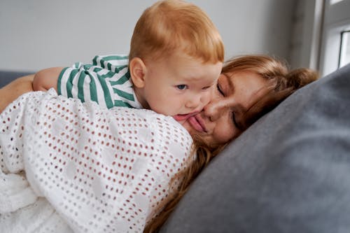 Free Mother embracing adorable baby on couch at home Stock Photo