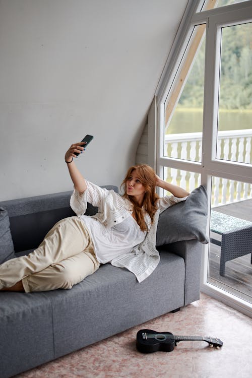 Woman on grey sofa taking selfie
