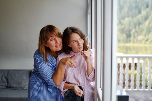 Women carefully looking out window together