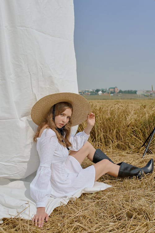 Trendige Frau Im Weißen Sommerkleid, Das Auf Landwirtschaftlichem Feld Sitzt