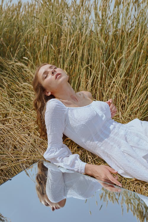 鏡の近くの芝生の牧草地に横たわる官能的な女性