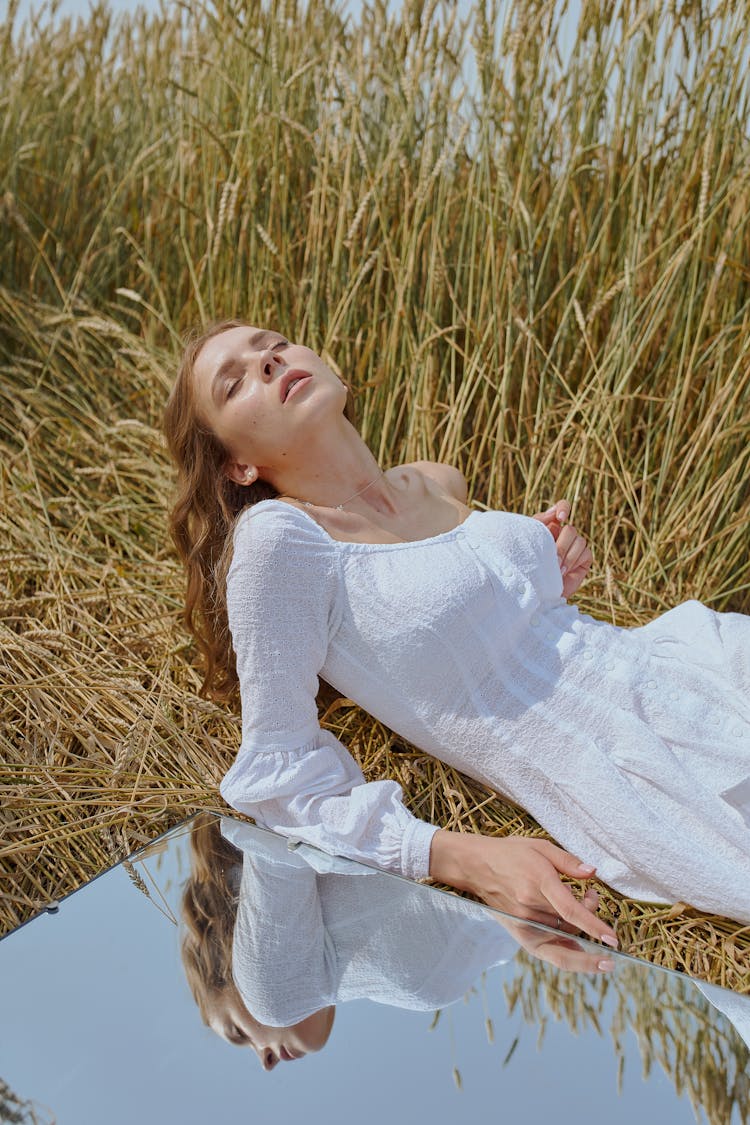 Sensual Woman Lying On Grassy Meadow Near Mirror