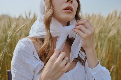 잔디 필드에 앉아 흰색 Headscarf에서 자르기 여자