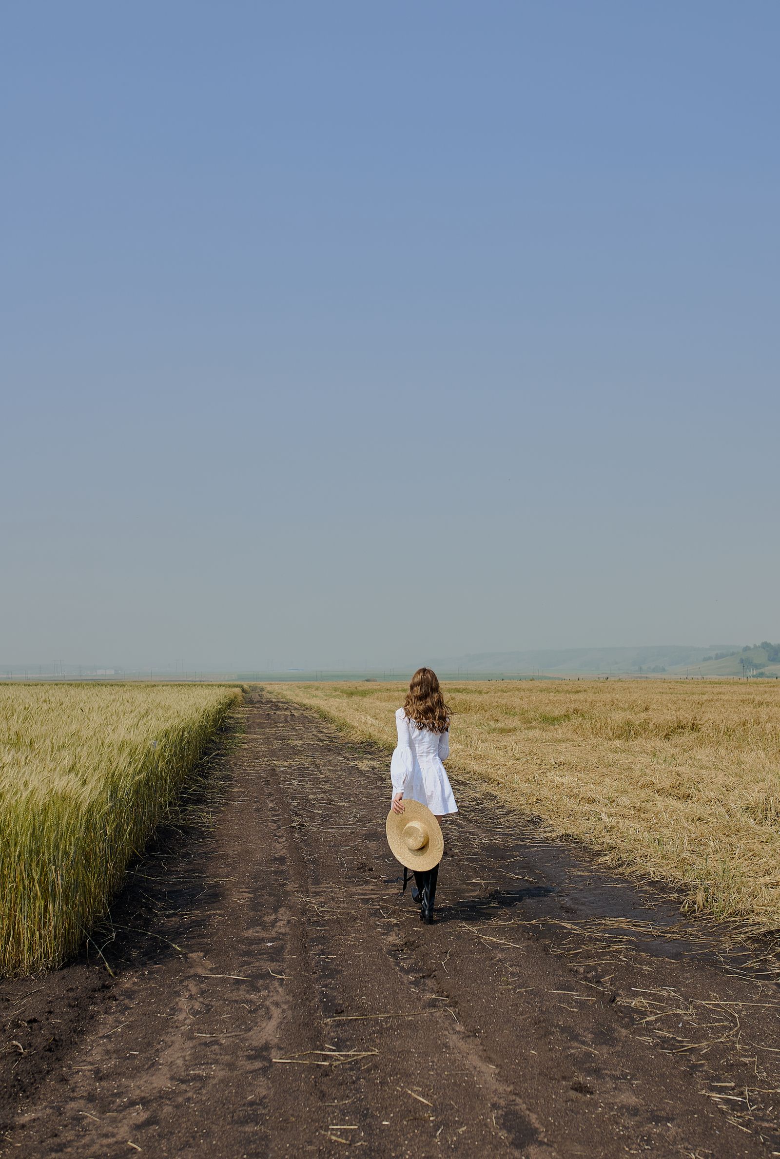 Modelo con vestido blanco caminando por un campo