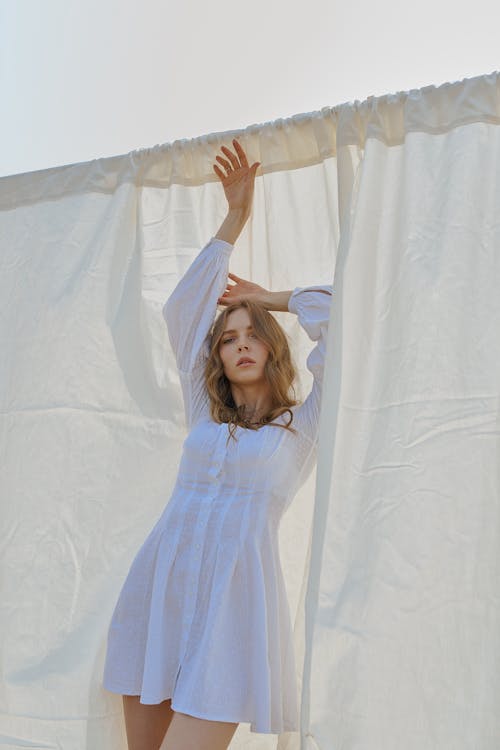 무료 세련된 여성 손을 들고 흰색 시트 근처에 서 스톡 사진
