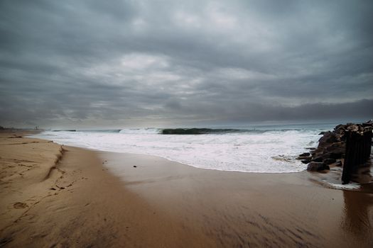 Serene beach with rolling waves and cloudy sky, perfect for coastal scenery lovers.